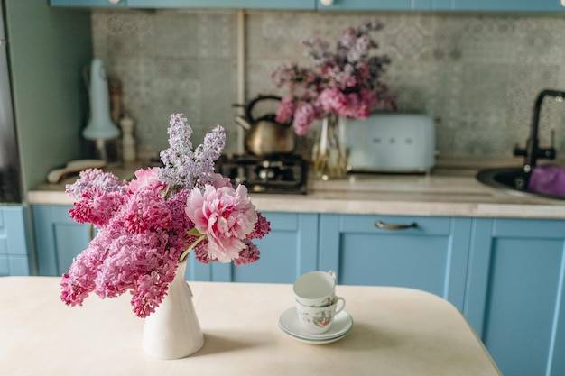 Ваза с лиловыми цветами стоит на кухонном стол