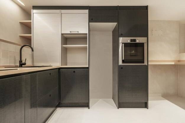 Кухня с зеленой мебелью, черными ручками, шкафом с алюминиевыми ставнями и пустым местом для холодильни