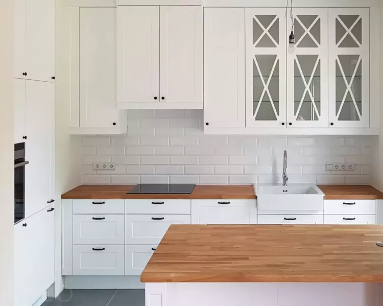 Классическая белая кухня островного типа с фасадами из крашенного МДФ, черными ручками и столешницей из массива дуб