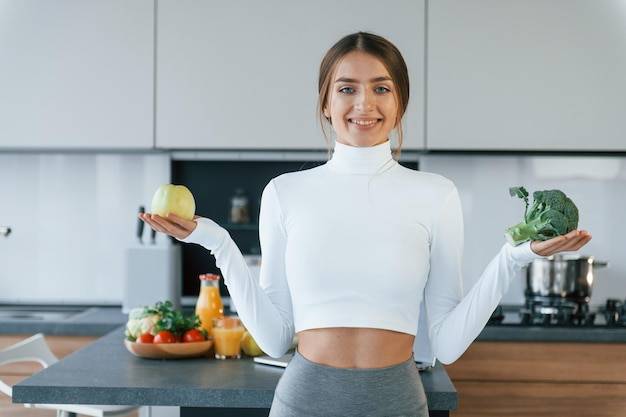 Позы для камеры с овощами молодая европейская женщина в помещении на кухне в помещении со здоровой едой