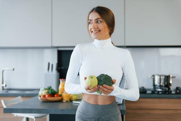 Позы для камеры с овощами молодая европейская женщина в помещении на кухне в помещении со здоровой едой