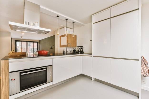 Белая кухня с белыми шкафами и черной духовкой