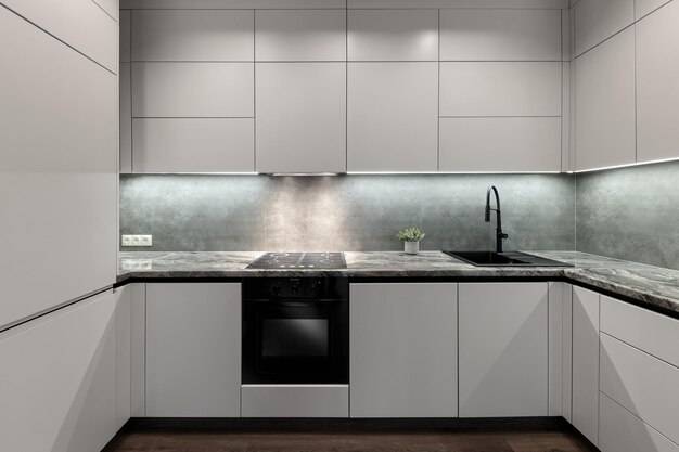 Интерьер кухни с дизайнерскими белыми шкафами с черным краном и черной духовкой и плитой