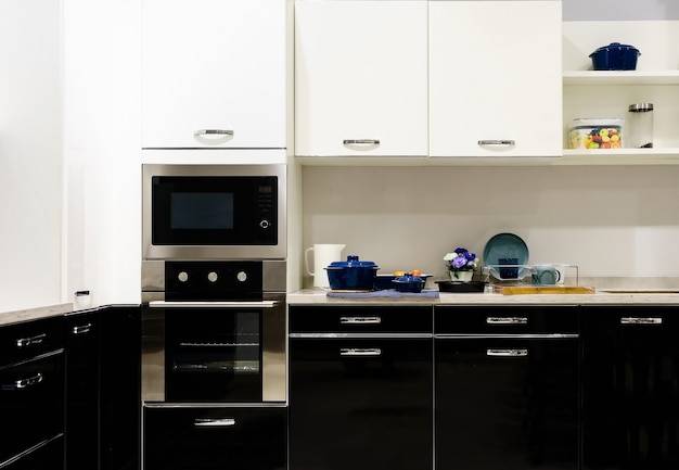 Кухонная мебель с современной посудой, как капот, черная индукционная печь и духов