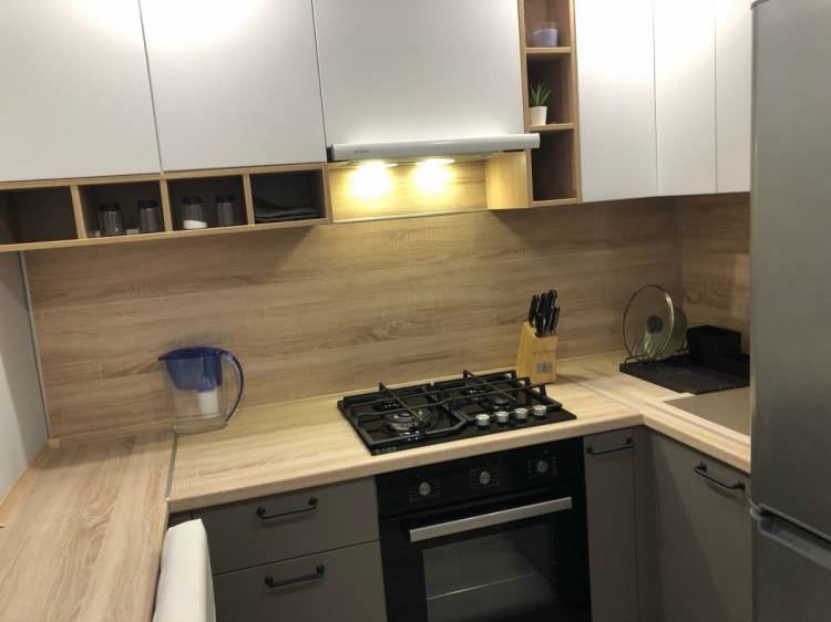 Современная Г-образная бело-серая кухня со столом вместо подоконника и столешницей под дерев