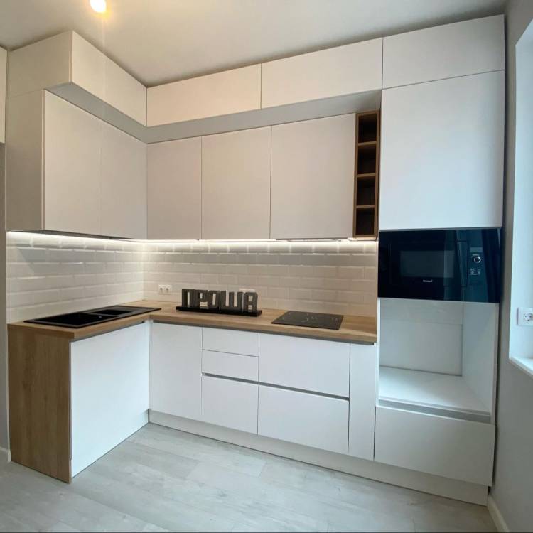 Белая матовая кухня с деревянной столешницей под потолок без ручек в ЖК