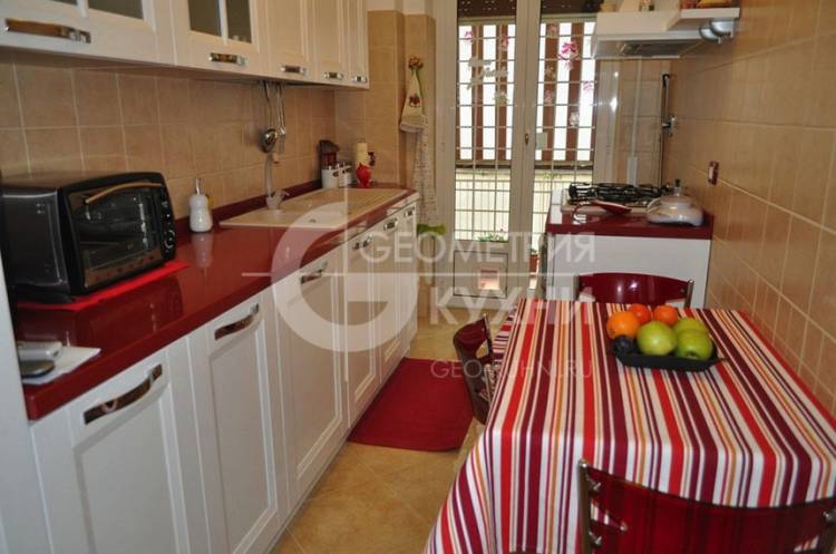 Белая прямая кухня с красной столешницей