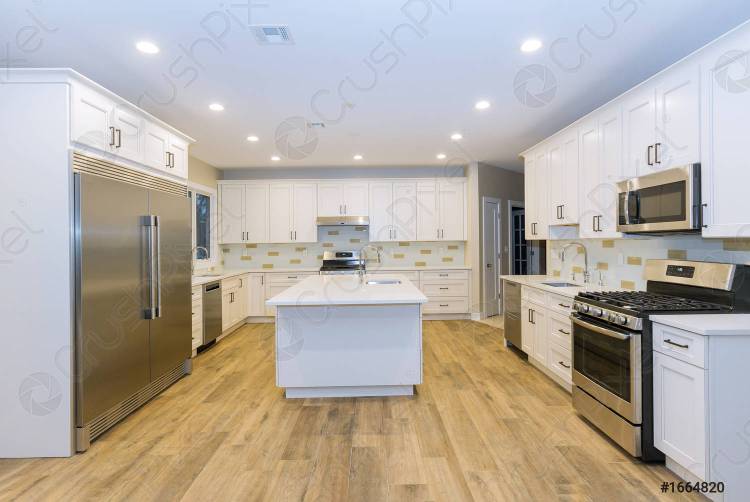 кухня с островными раковинами и деревянными полами в новом роскошном доме три кухонные раковины