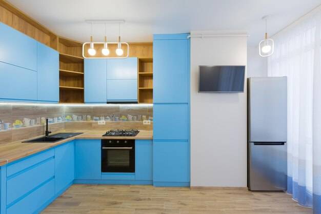 Интерьер большой голубой кухни с деревом в квартир