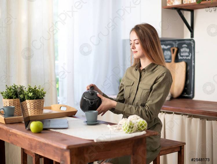дома на кухне работает молодая красивая девушка и общается на ноутбуке за завтраком по утрам
