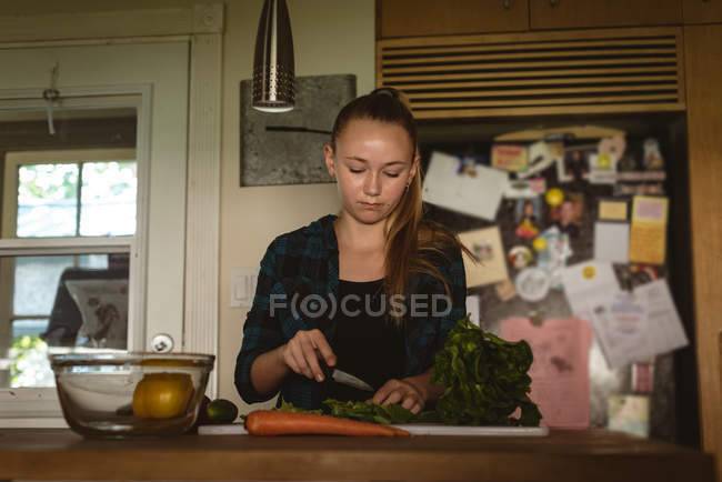 Девушка стоит на кухне и режет овощи ножом дом