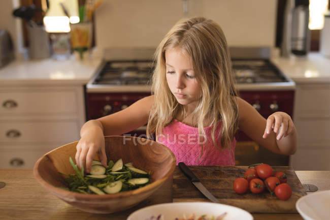 Девушка готовит еду на кухне дома, салат с огурцами и помидорами