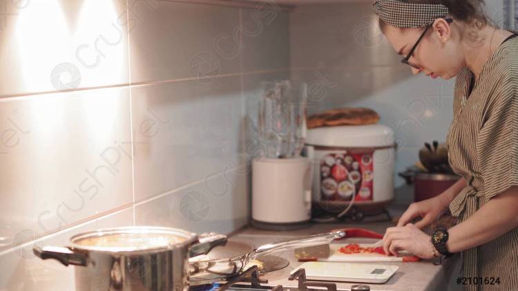 симпатичная женщина готовит суп на плите на кухне крупным планом домохозяйка готовит ужин дома молодая женщина дегустирует суп на ложке на современной кух