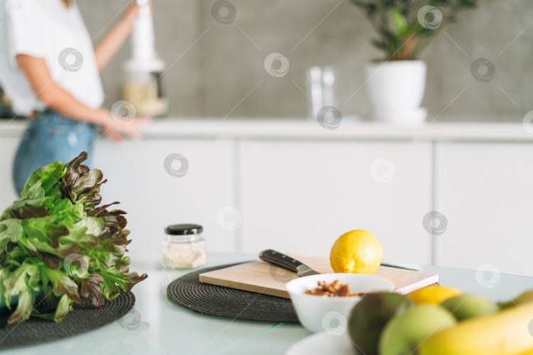 Свежие зеленые полезные фрукты и овощи на столе, пока женщина готовит смузи на кухне дом
