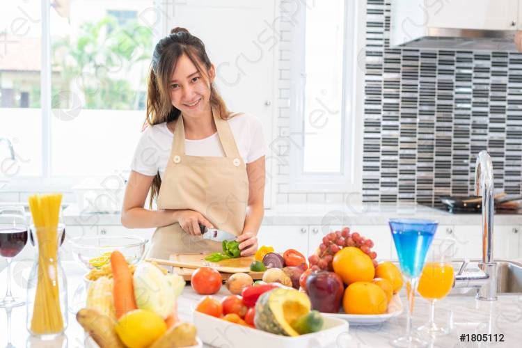 Красавица, готовая и нарезающая в кухонной комнате с полным набором еды и фруктов на столе для праздника и концепции счастья люди и лайки концепт девушка, смотрящая в камеру