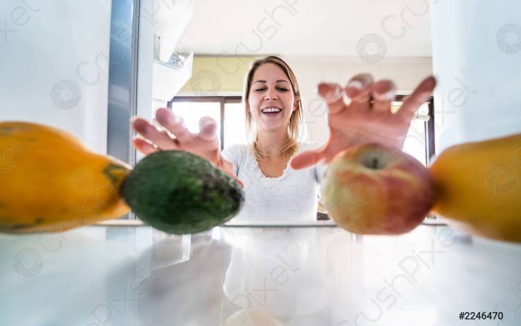 молодая женщина на кухне, выбирая органические фрукты для приготовления свежего экстрактивного с