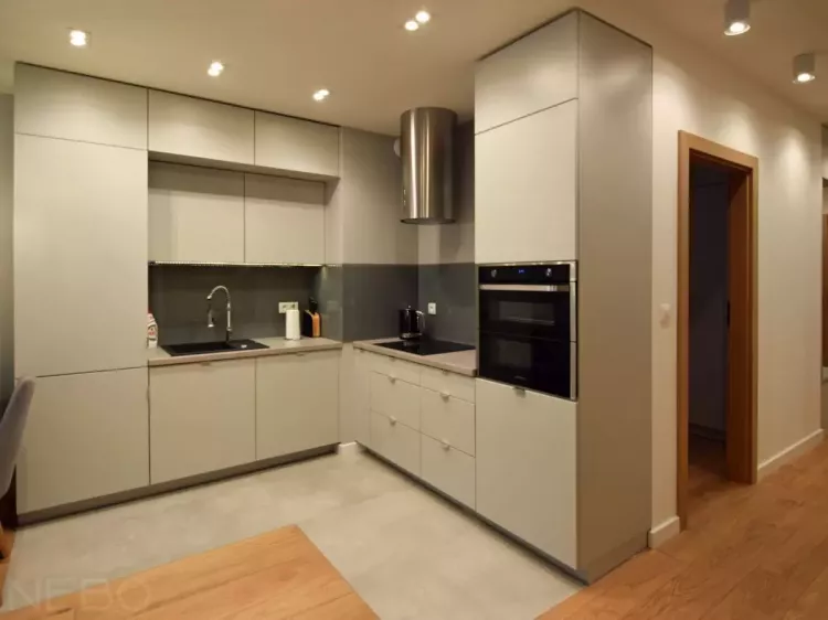Угловая кухня в серых тонах с фасадами из крашенного МДФ, фартуком из стекла, подсветкой рабочей зоны и столешницей из постформинг