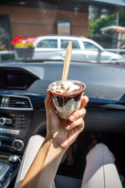 Женщина держит мороженое mcdonalds mcflurry с шоколадом в машине после проезда чер
