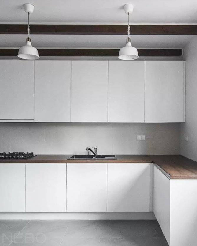 Белая кухня с интегрированными ручками и столешницей из постформинга под темное дерево, изготовленная по индивидуальным размерам и проекту
