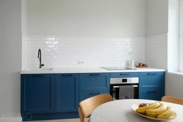 Маленькая синяя кухня без верхних шкафов и с белой столешницей